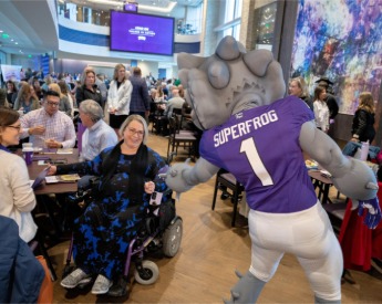 Legends club event with SuperFrog shaking the hand of a seated TCU staff member